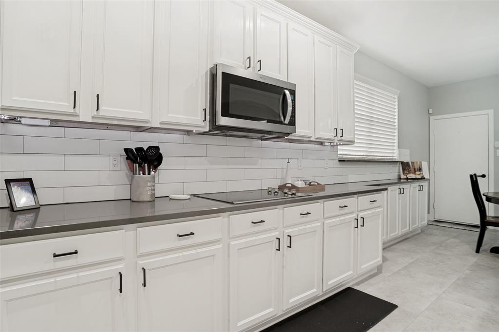 1612 Coventry Lane Allen, TX 75002 - Photo 27 of 39 Kitchen featuring extensive white cabinetry with black hardware, dark countertops, and a subway tile backsplash