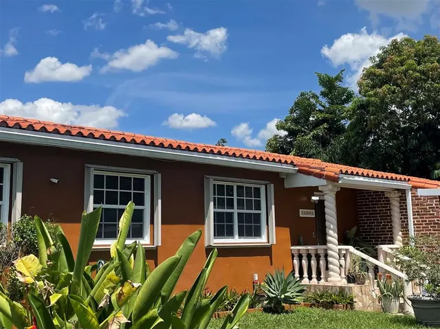 a front view of a house with a large window and potted plants