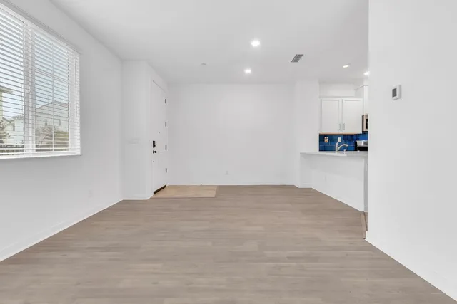 a view of an empty room with kitchen and a window