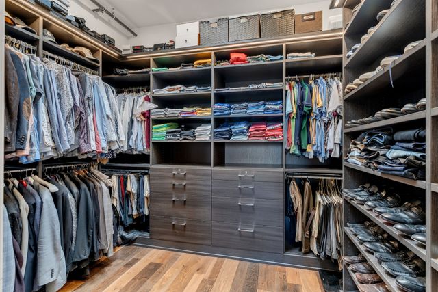 a view of walk in closet with clothes and shoes