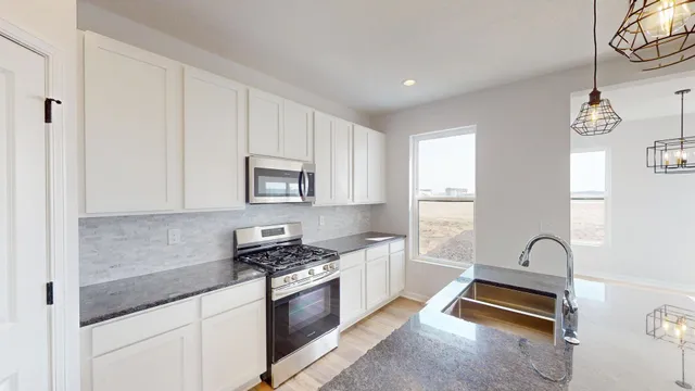 a kitchen with stainless steel appliances granite countertop a stove a sink and white cabinets