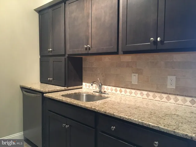 a kitchen with granite countertop white cabinets and a sink