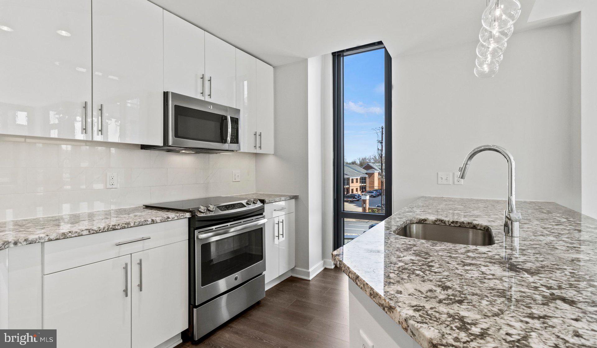 8300 Wisconsin Avenue, Unit 1B1831 Bethesda, MD 20814 - Photo 103 of 150 a kitchen with stainless steel appliances granite countertop a stove a sink and a microwave