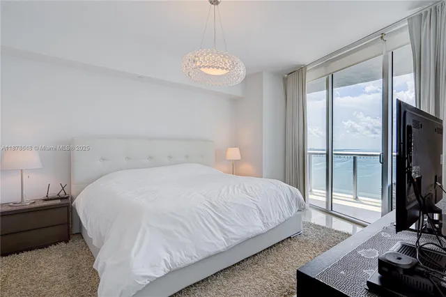 a bedroom with a bed and a flat tv screen on dresser