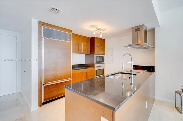 a kitchen with stainless steel appliances granite countertop a sink and a refrigerator