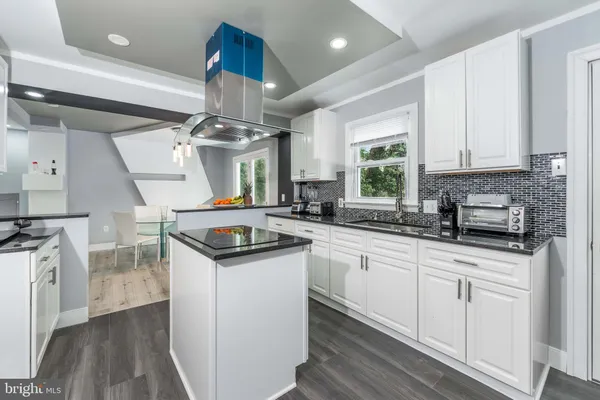 a kitchen with granite countertop a sink cabinets stainless steel appliances and wooden floor