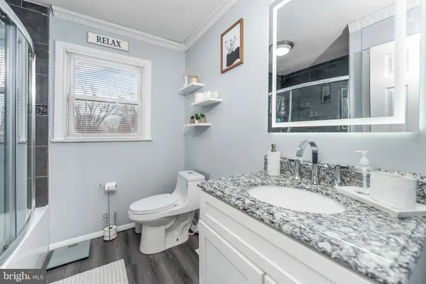 a bathroom with a granite countertop toilet a sink and a mirror