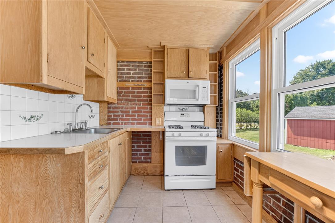 1166 Stones Crossing Road Easton, PA 18045 - Photo 16 of 35 A well-lit kitchen with natural wood cabinetry and a view of the garden.