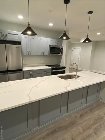 a kitchen with kitchen island a sink stainless steel appliances and chairs