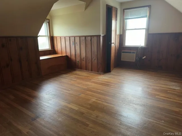 an empty room with wooden floor windows and entryway