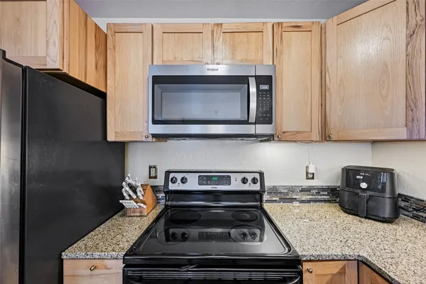 a kitchen with stainless steel appliances granite countertop a sink refrigerator and microwave