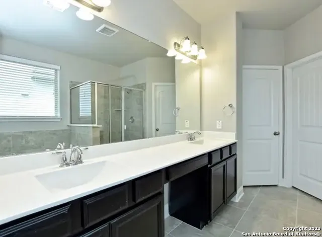 a bathroom with a double vanity sink a mirror and a shower