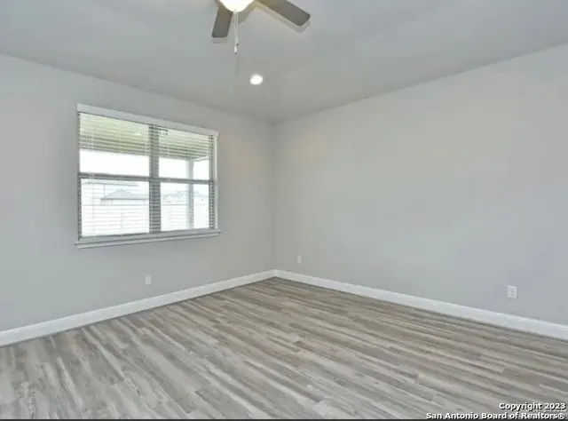 an empty room with a window and ceiling fan