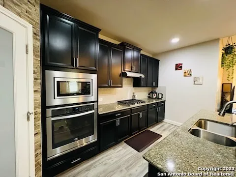 a kitchen with stainless steel appliances granite countertop a sink stove and microwave