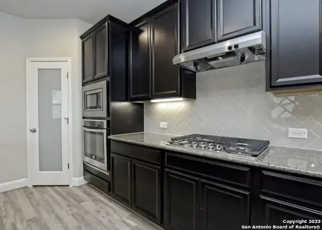 a kitchen with stainless steel appliances granite countertop a refrigerator and a stove