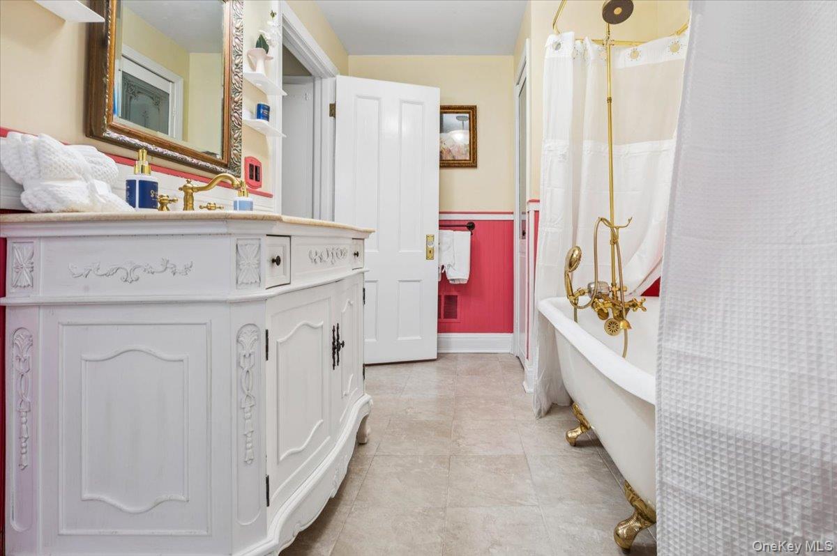 46 Bedford Road Katonah, NY 10536 - Photo 15 of 34 White carved vanity with a light-toned countertop, brass-finish faucet, and an ornate mirror