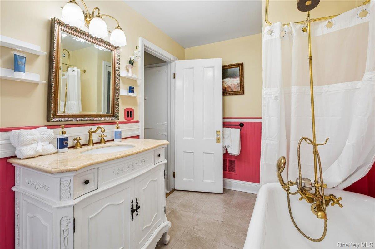 46 Bedford Road Katonah, NY 10536 - Photo 17 of 34 Bathroom featuring a white vanity with an undermount sink, brass-finish faucet, and a light-toned countertop