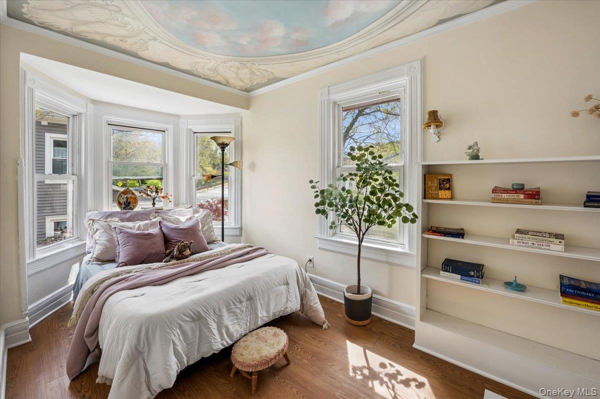 46 Bedford Road Katonah, NY 10536 - Photo 18 of 34 Room featuring a decorative ceiling mural, wood-finish flooring, a bay window with three large panes, built-in shelving, and white trim throughout