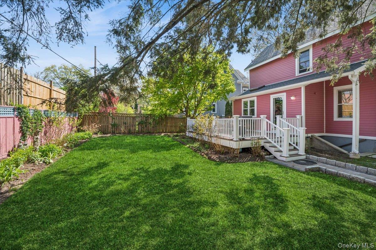 46 Bedford Road Katonah, NY 10536 - Photo 28 of 34 Expansive green lawn with surrounding garden beds, bordered by a wooden privacy fence