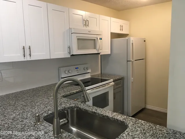 a kitchen with granite countertop a stove sink and refrigerator