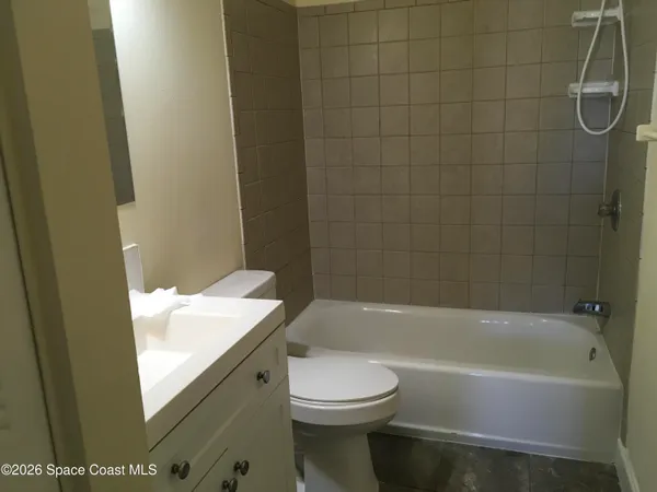 a bathroom with a granite countertop bathtub shower sink vanity and toilet