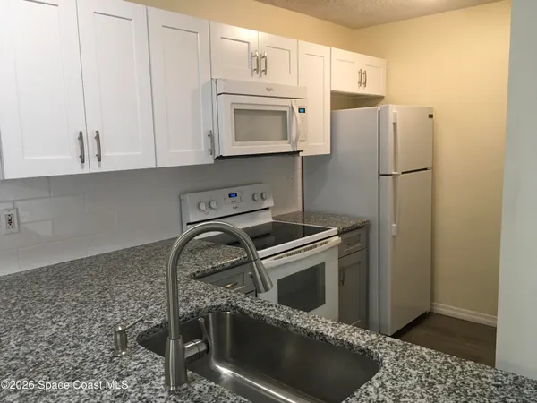 a kitchen with granite countertop a stove sink and refrigerator