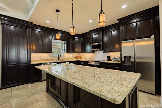 a kitchen with stainless steel appliances granite countertop wooden cabinets a sink and a refrigerator