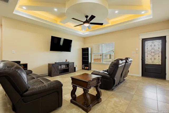 a living room with furniture a ceiling fan and a flat screen tv