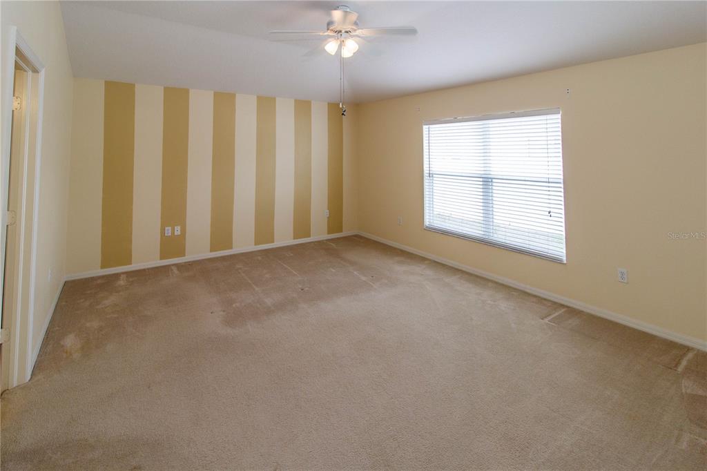 1747 Ravenridge Street Wesley Chapel, FL 33543 - Photo 22 of 35 an empty room with chandelier fan and windows