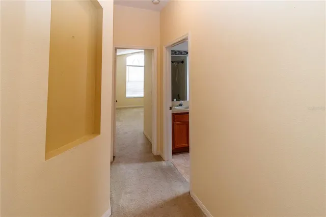 a view of a hallway with wooden floor and a bathroom