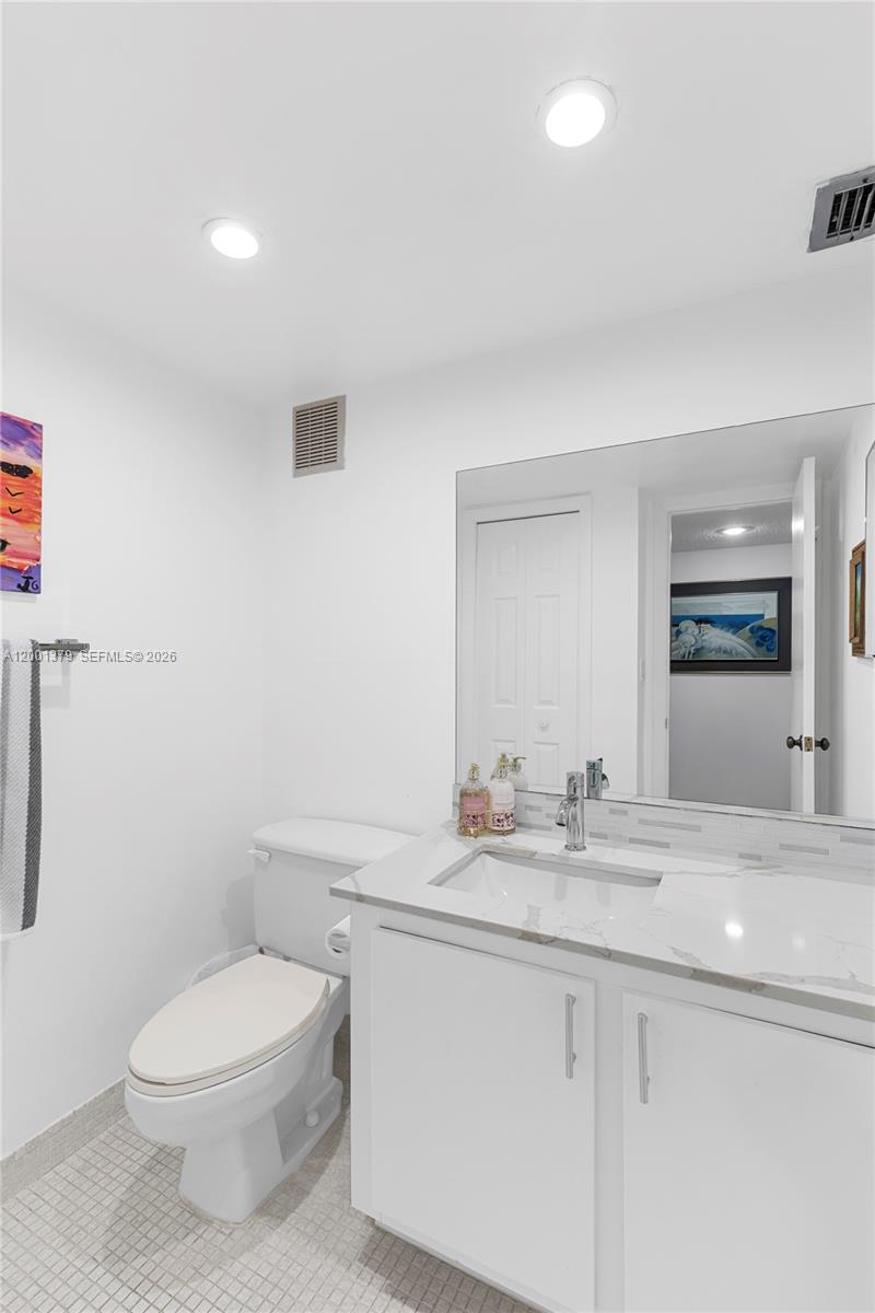 16251 Golf Club Road, Unit 311 Weston, FL 33326 - Photo 10 of 38 a bathroom with a granite countertop toilet sink mirror and vanity