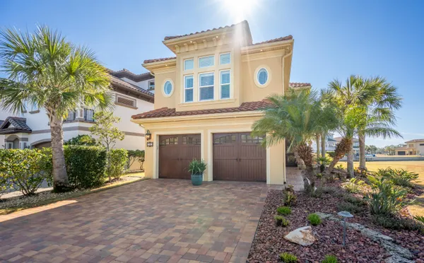 a front view of a house with a yard and palm trees