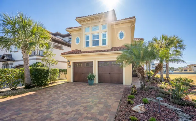 a front view of a house with a yard and palm trees