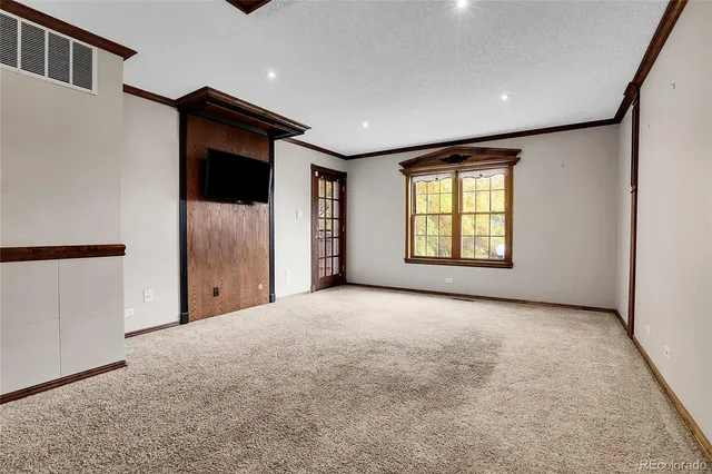 a view of an empty room with a window and a kitchen