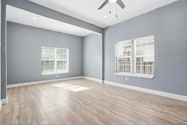 a view of an empty room with wooden floor and a window
