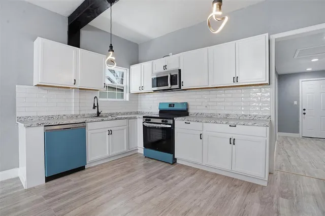 a kitchen with cabinets stainless steel appliances a sink and wooden floor