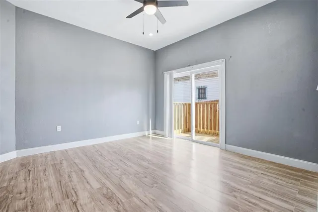a view of an empty room with a window and wooden floor