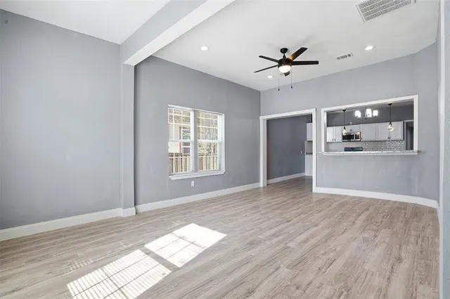 a view of an empty room with a window and wooden floor