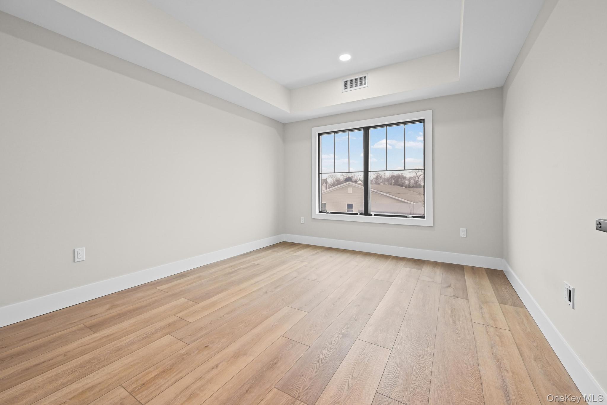 80 Division Street, Unit 2B Patchogue, NY 11772 - Photo 8 of 13 wooden floor in an empty room with a window