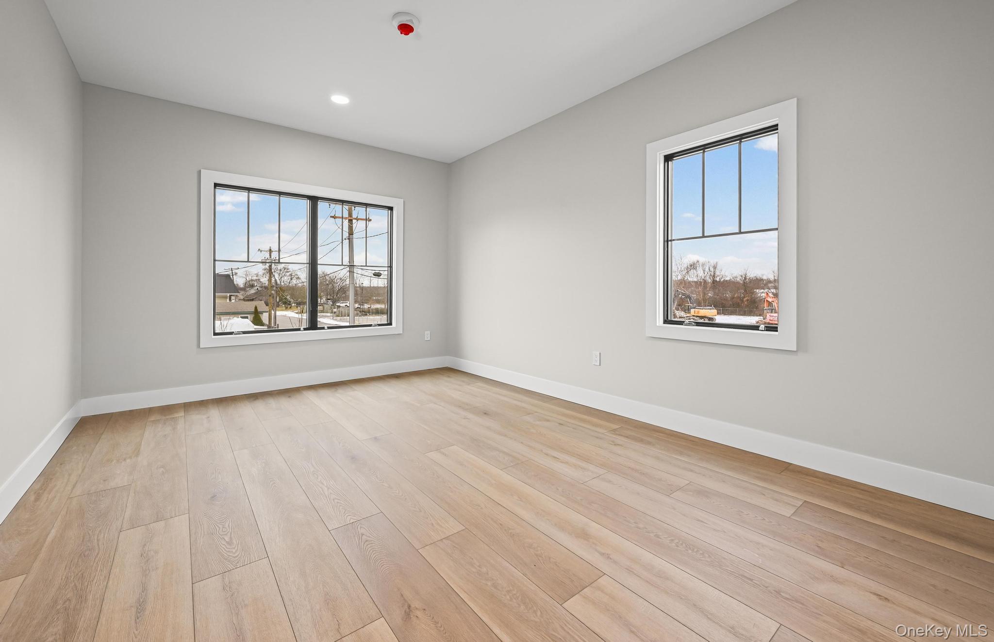 80 Division Street, Unit 2B Patchogue, NY 11772 - Photo 9 of 13 a view of an empty room with wooden floor and a window