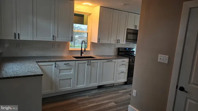 a kitchen with granite countertop a sink and white cabinets