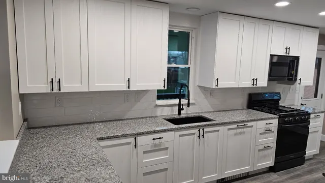 a kitchen with granite countertop a stove and a microwave