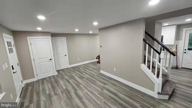 a view of a hallway with wooden floor and a bathroom