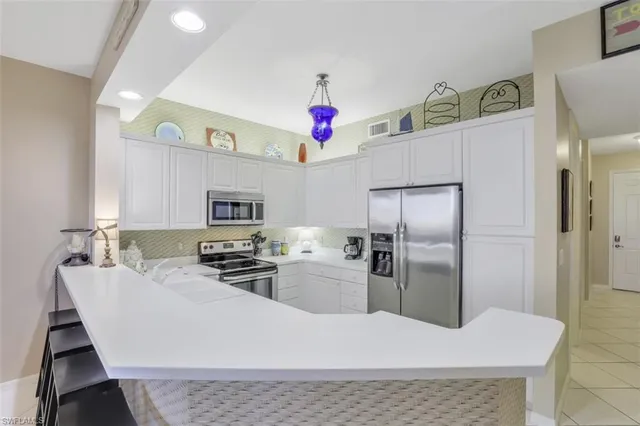 a kitchen with stainless steel appliances kitchen island granite countertop a refrigerator a stove top oven a sink and dishwasher