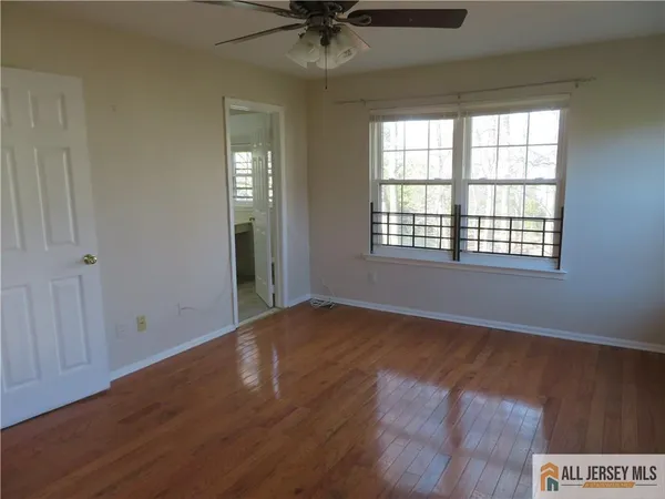 a view of an empty room with a window and wooden floor