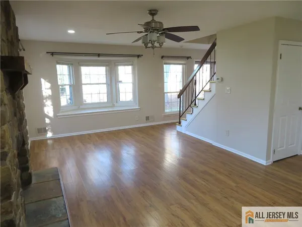 an empty room with windows fireplace and wooden floor