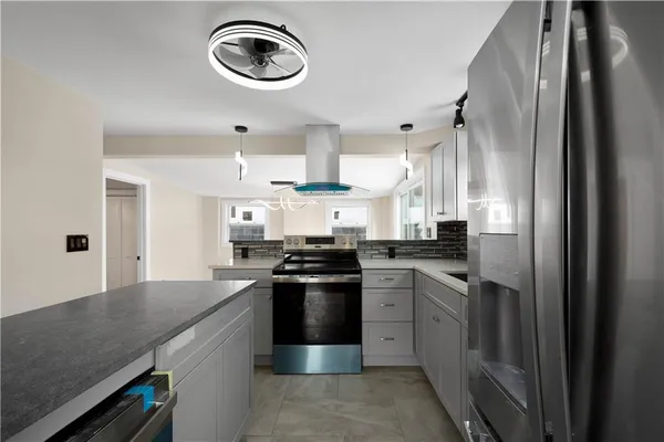 a kitchen with stainless steel appliances granite countertop a stove a sink dishwasher and a refrigerator with wooden floor