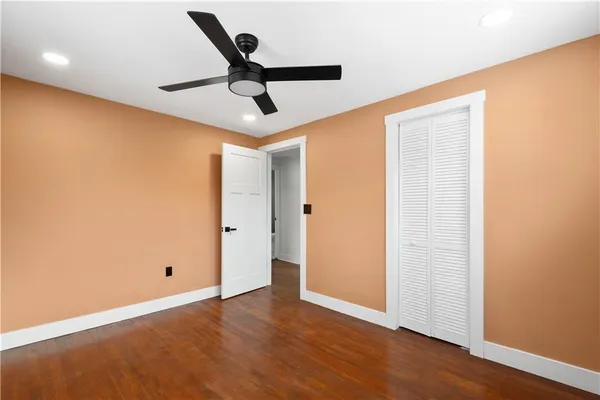 an empty room with wooden floor and ceiling fan
