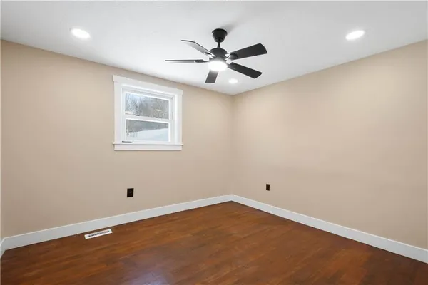 an empty room with wooden floor and ceiling fan