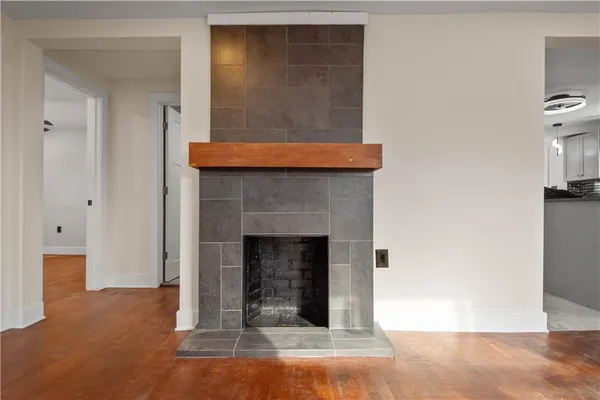 a view of an empty room with wooden floor and a fireplace